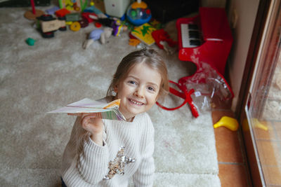 High angle portrait of girl playing with paper airplane 
