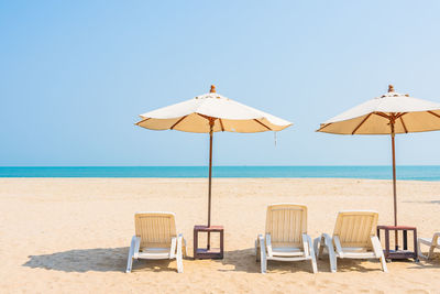 Deck chairs on beach against clear sky