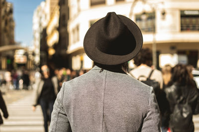 Rear view of man standing on street in city during sunny day