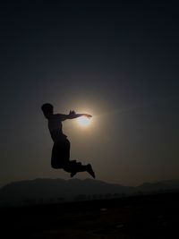Side view of man jumping against sky during sunset