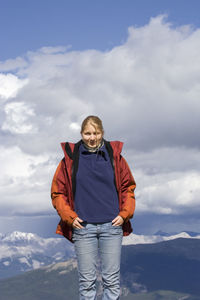 Portrait of woman standing on whistler mountain against cloudy sky during winter