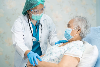 Doctor wearing mask consoling patient at hospital