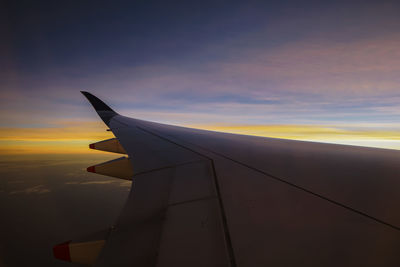 Airplane wing against sky during sunset