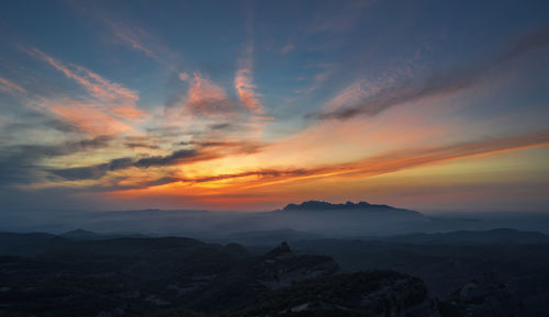 Scenic view of silhouette mountains against orange sky