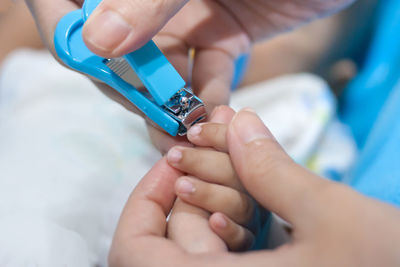 Close-up of mother cutting nails of baby at home