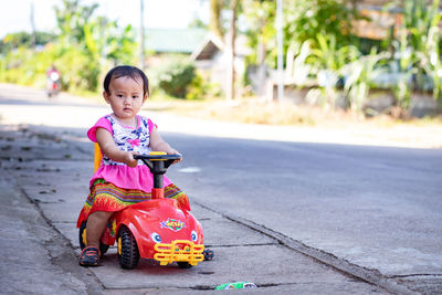 Girl looking away while sitting on road