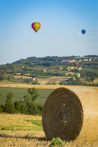 Hot air balloons flying over field against sky