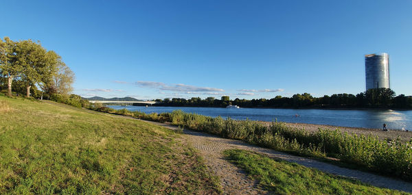 Scenic view of river by field against blue sky