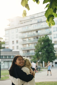 Smiling female friends embracing at park