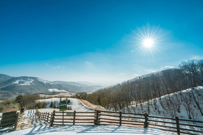 Snow covered landscape against blue sky