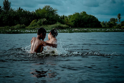 Friends enjoying in water against sky