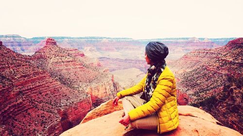 Rear view of woman standing on rock against sky