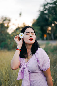 Young woman holding pink while standing on field