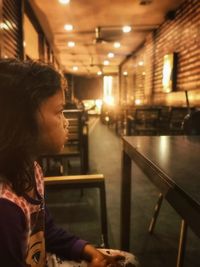 Side view of woman looking at illuminated subway