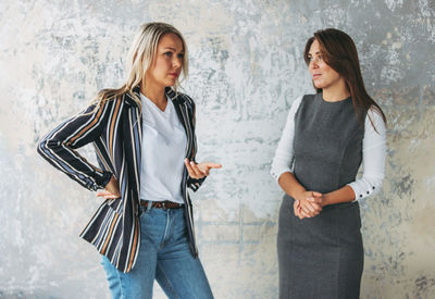 Woman discussing with colleague against wall