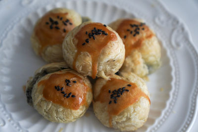 There are some delicious black sesame egg yolk pastries freshly baked on the plate on the table