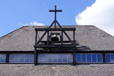 Low angle view of cross on building against sky