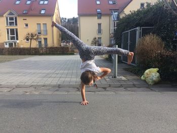 Full length of young woman doing handstand on road