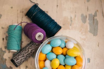 High angle view of candies in bowl with threads on table