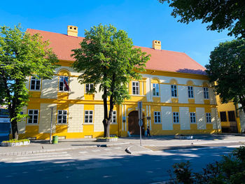 Residential building by road against blue sky