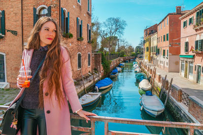 Portrait of smiling young woman standing in canal