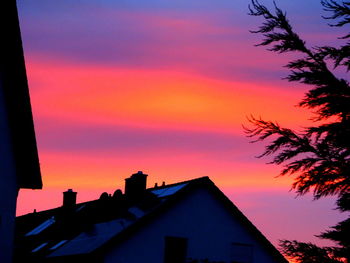 Silhouette houses against sky during sunset