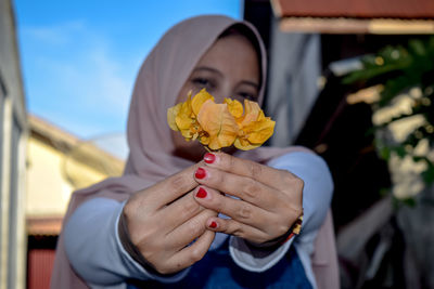 Midsection of woman holding yellow flower