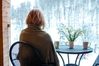 Rear view of woman sitting at table during winter