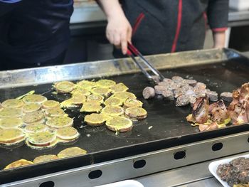Midsection of person preparing food on barbecue grill