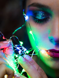 Close-up of woman holding illuminated string light