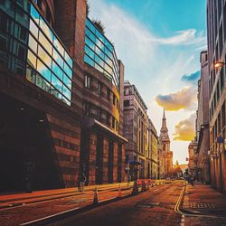 Street amidst buildings in city during sunset