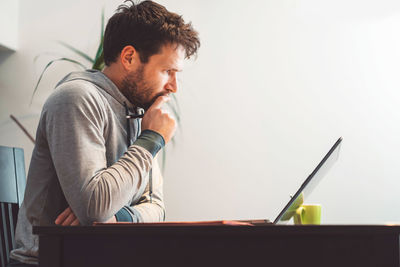 Side view of man using laptop at home