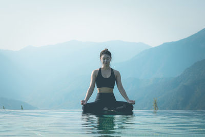 Woman exercising against lake and mountains