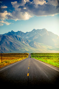 Road leading towards mountains against sky