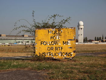 Information sign on field against sky