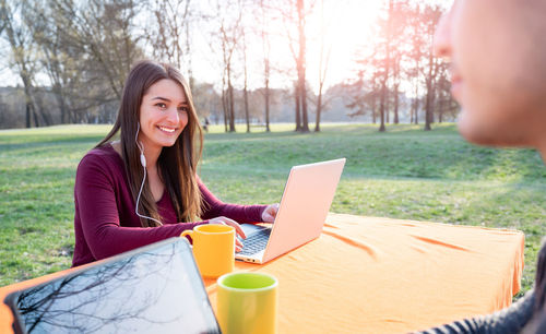 Young woman using laptop while sitting on field