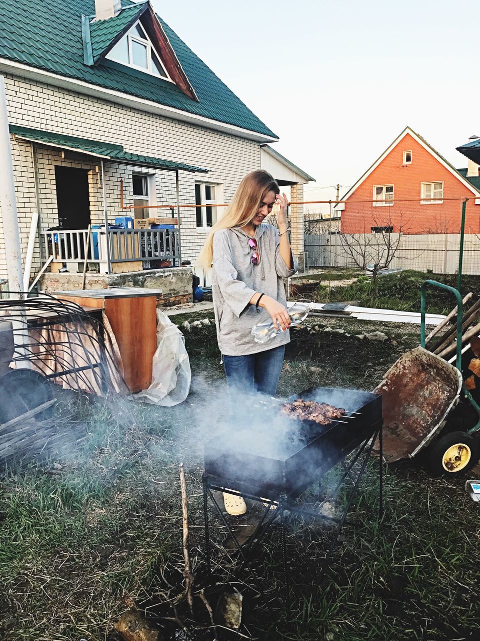 building exterior, house, architecture, one person, built structure, smoke - physical structure, casual clothing, outdoors, full length, day, real people, women, blond hair, young women, one woman only, sky, young adult, people, adult, adults only