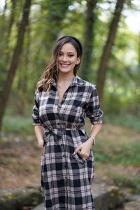 Portrait of smiling young woman standing in forest