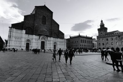 Group of people in town square against buildings in city