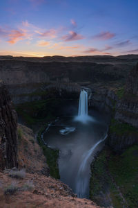 Scenic view of waterfall against sky during sunset