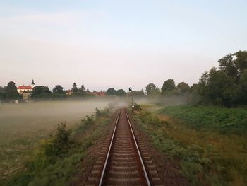 Railroad tracks by trees against sky