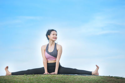 Woman doing yoga against sky