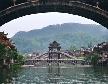 Arch bridge over river with buildings in background