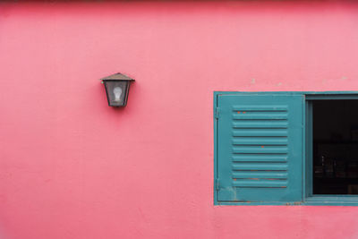 Scenic view of a closed windows next to a lamp on a pink wall