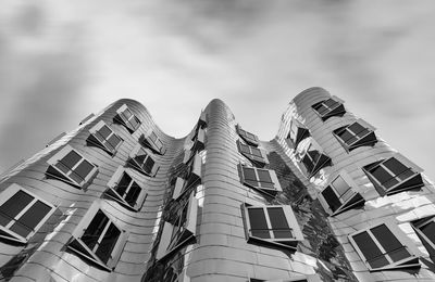 Low angle view of buildings against cloudy sky