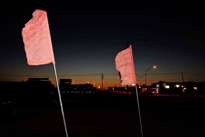 Red flag by street against sky at night