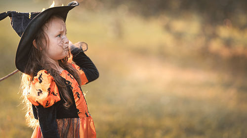 Girl looking away while standing on field