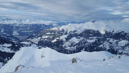 Scenic view of snowcapped mountains against cloudy sky during winter