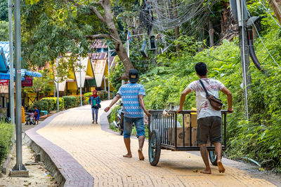 Rear view of people walking on footpath