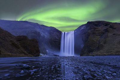 Flash of aurora polaris above skogafoss waterfall, iceland